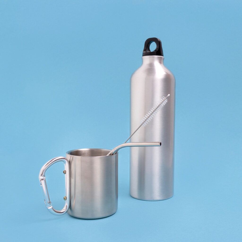 Stainless steel bottle, cup, drink tube and cleaning brush on a blue background.
